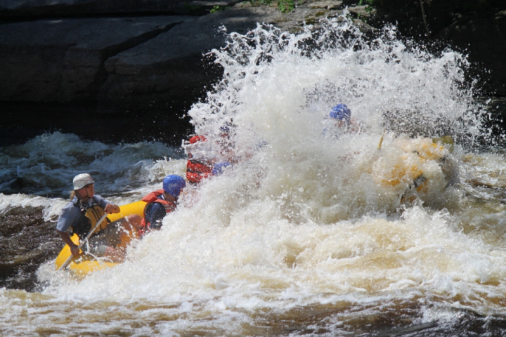 a man riding a wave on a raft in a body of water